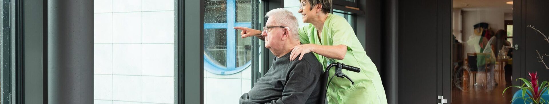 Bewohner und Pflegerin schauen aus dem Fenster